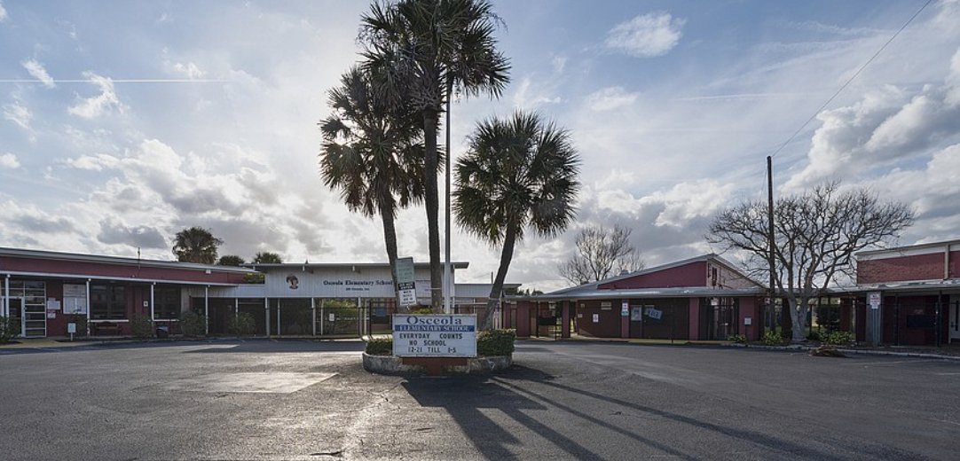 The former Osceola Elementary School campus on Osceola Avenue in Ormond Beach, with palm trees in front of the red school buildings.